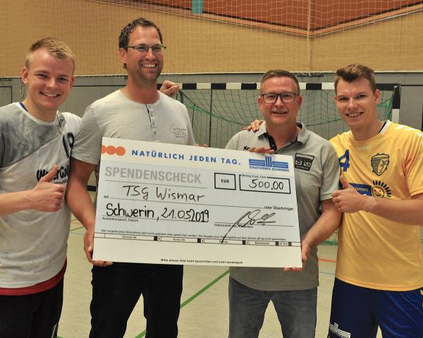 Aurel Witt (2.v.li.) vom Tourpartner Stadtwerke Schwerin übergibt eine Spende in Höhe von 500 Euro an TSG-Coach Sven Hünerbein. Mit dabei: die Spieler Marc Hünerbein (TSG/li.) und Tobias Grämke von den Handballstieren.